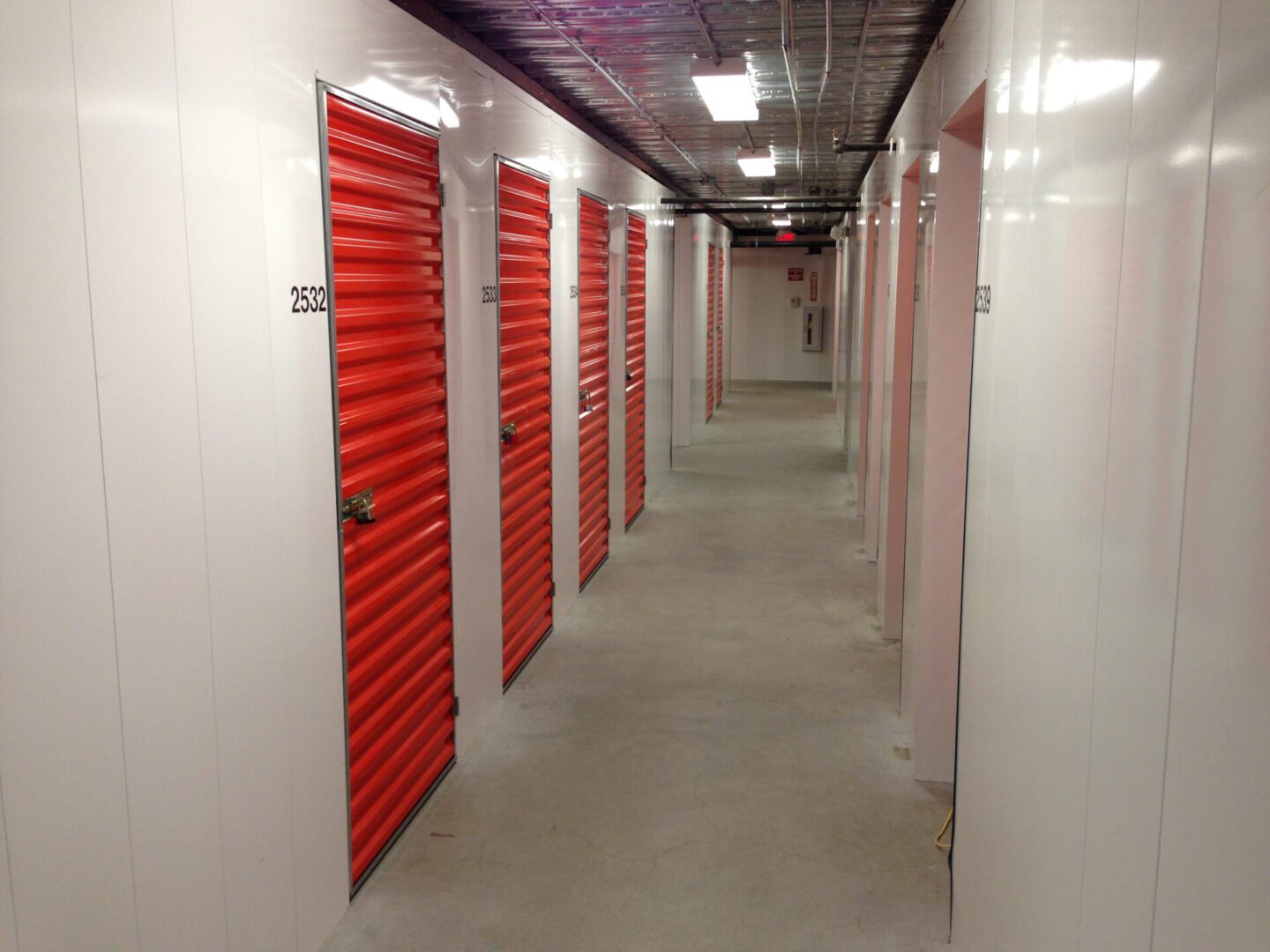 Self storage facility Storage units with red doors in hallway.