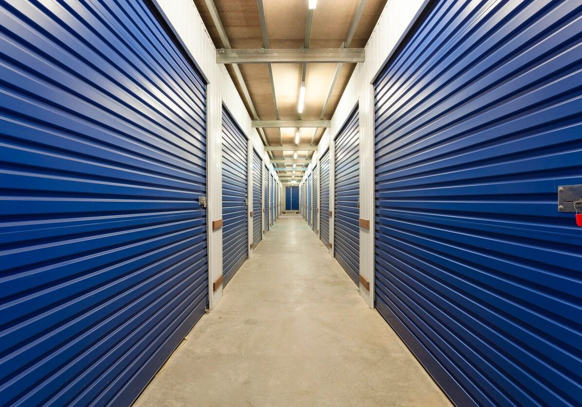 A long hallway of self-storage units with blue doors.